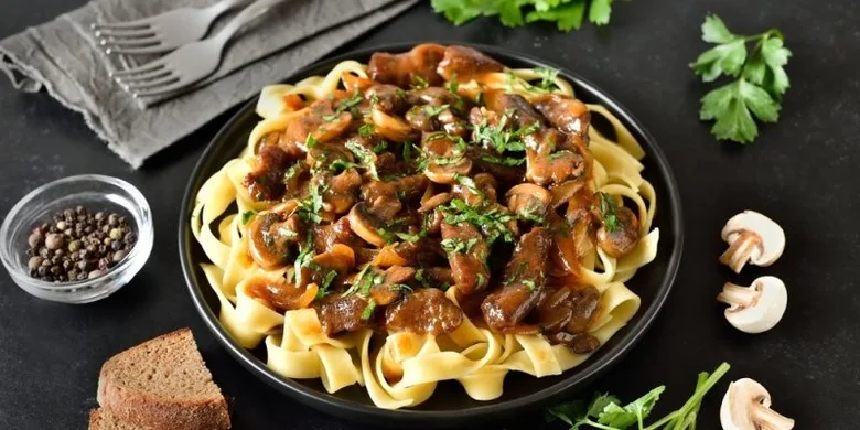 Pasta s houbami a masem na tmavém podkladu
