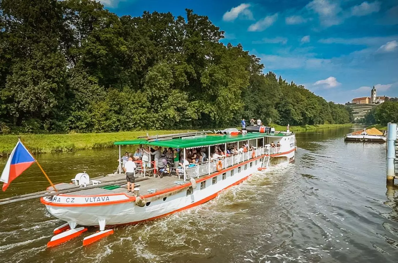 Turistická loď pluje po řece Vltavě v Praze.