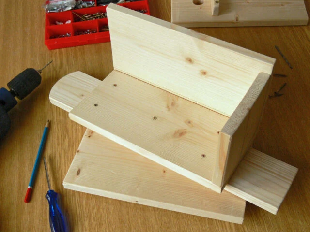 Stavba dřevěné ptačí budky s nástroji na pracovním stole.