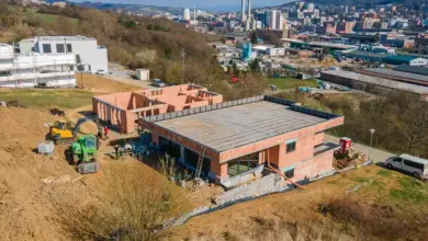 Stavba na svahu s nedokončenými domy v krajině u města.